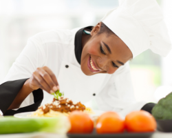 A cook decorates a plate with food on it
